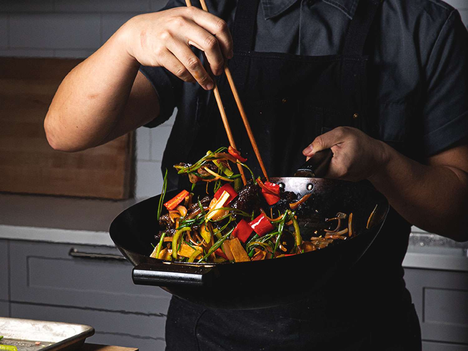 Hands preparing a colourful vegetable stir-fry in a home kitchen